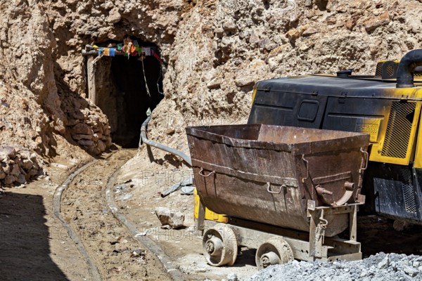 A mine car and a machine near the entrance of a rocky mine, The silver mines of the Cerro Rico