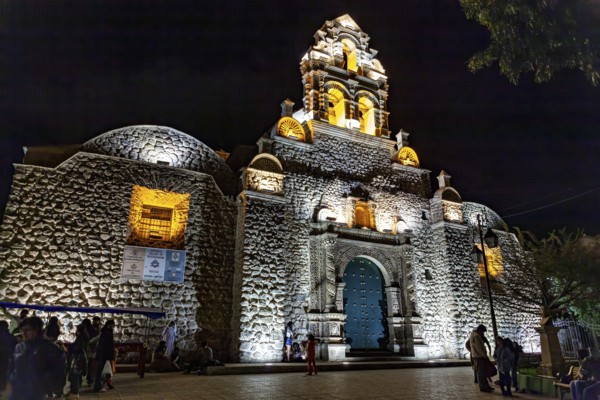 Illuminated church at night with impressive architecture and blue Tor tor, surrounded by evening