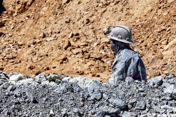 A miner gazes into the distance, surrounded by rocks and dusty terrain, The miners of the Cerro