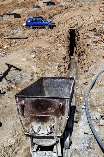 An old mining wagon stands next to a trench in an arid landscape, The silver mines of Potosi