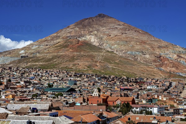 City at the foot of a large, barren mountain under a clear sky, the Cerro Rico silver mountain in