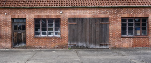 View of the entrance area of an older residential building with a red brick workshop, Uenzen,