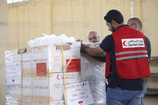 Relief workers unload boxes of medical aid provided by Qatar at Damascus International Airport,