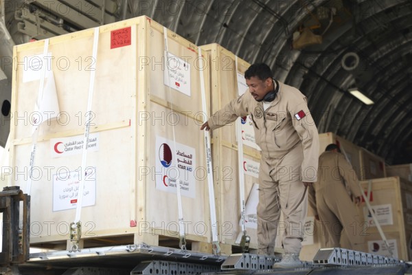 Members of the Qatari Air Force unload humanitarian aid supplies from a transport aircraft at