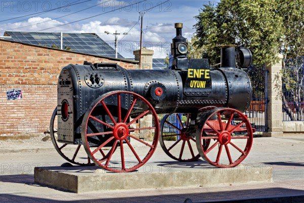 Old steam engine with red wheels stands on a pedestal in the open air in Bolivia, Old historic