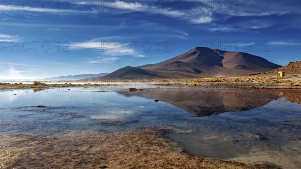 Peaceful mountain landscape with a clear lake and clouds in the sky creating a tranquil atmosphere,