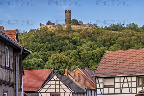 A quiet village scene with half-timbered houses and a castle on a hill, the ruins of Mühlburg