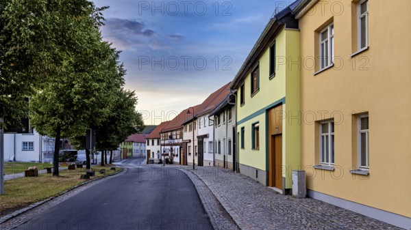 Row of houses in a quiet street with colourful facades and evening sky, the village of Mühlburg in