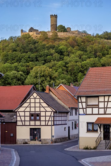 A village with half-timbered houses and a hill with a castle in the background, the ruin Mühlburg