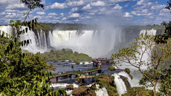 Dense vegetation surrounds a platform from which visitors can view the waterfalls, The Iguazu Falls