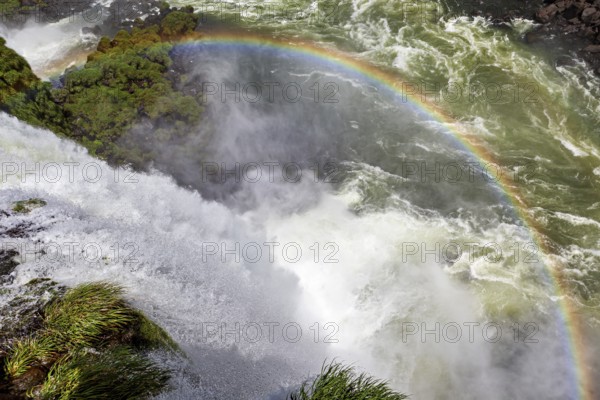 A glowing rainbow appears over a thundering waterfall, The Iguazu Falls between Argentina and