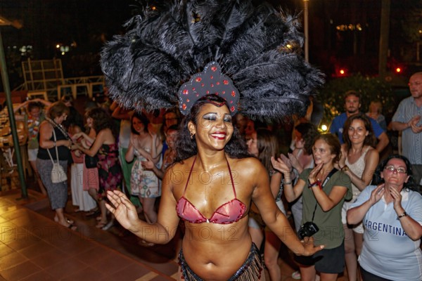 Dancer with feather headdress dances in front of an applauding audience, Samba dancers to entertain