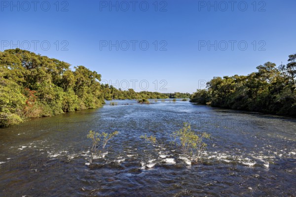 Long river flows through a green landscape under a clear blue sky, The Iguazu River between