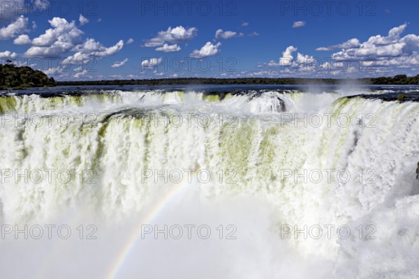 Spectacular waterfall with rainbow and spray under a cloudy sky, The Iguazu Falls between Argentina