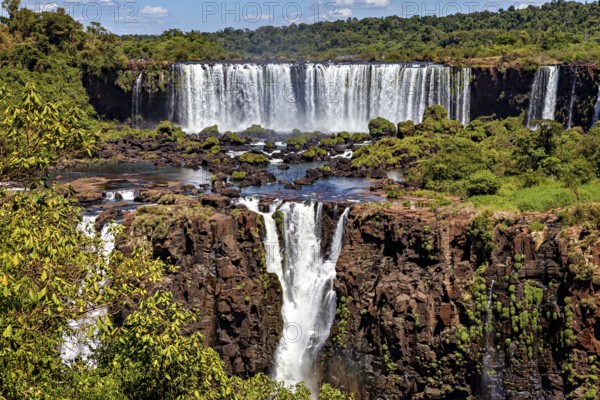 Waterfalls in a rocky landscape with river and lush vegetation, clear sky, The waterfalls of Iguazu