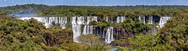 Wide panoramic view of a series of waterfalls in a green setting, The Iguazu Falls between