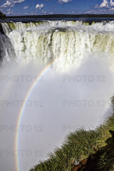 Dramatic waterfall with rainbow and spray under a blue sky, The Iguazu Falls between Argentina and