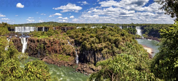Sweeping views of waterfalls and river, surrounded by lush vegetation under a cloudy sky, The