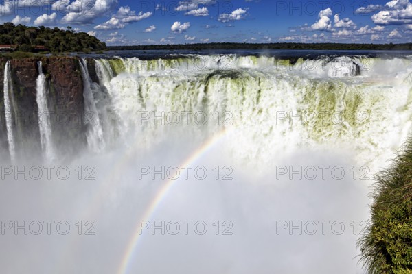 Majestic waterfall with rainbow and spray under a cloudy sky, The Iguazu Falls between Argentina