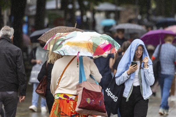Rainy weather in Stuttgart. People with umbrellas hurry through the rain on Königstraße. Stuttgart,