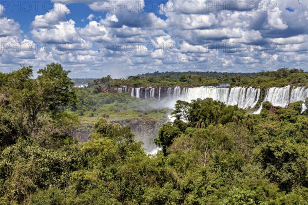 Dense vegetation frames impressive waterfalls under a cloudy sky, The Iguazu Falls between