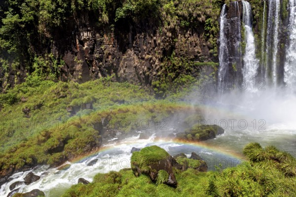 Rainbow over gushing water of a waterfall in green surroundings, The waterfalls of the Iguazu