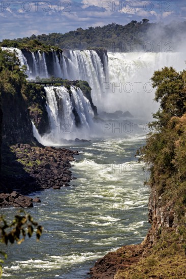 Impressive waterfalls with strong currents, surrounded by rocks and lush vegetation, The Iguazu