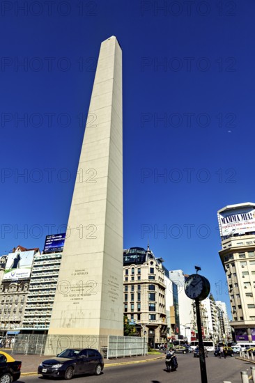 A tall obelisk under a clear blue sky surrounded by modern buildings, The Great Obelisk in the city