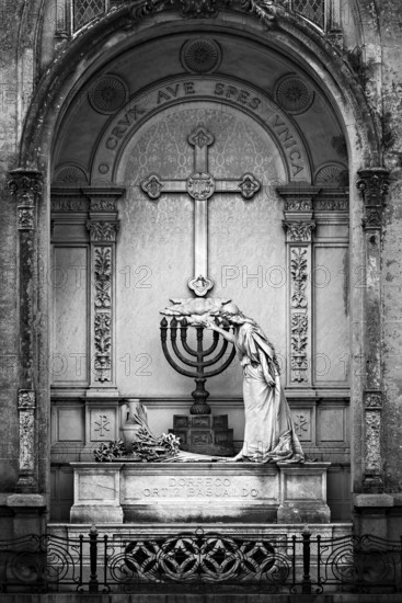 Black and white image of a statue and cross in an ornate mausoleum, La Recoleta Cemetery in Buenos
