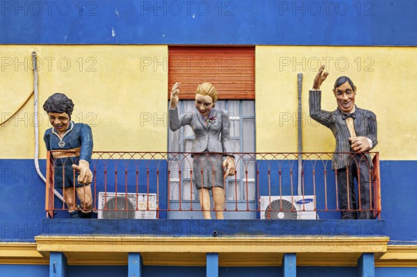 Three figures on a balcony of a historically painted building, The colourful city and tango