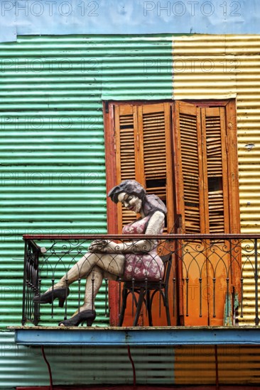 Female figure on a balcony in front of a striped façade, The colourful city and tango district of