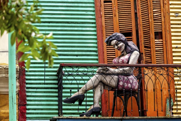 Sculpture of a woman on a balcony in front of a colourful façade, The colourful city and tango