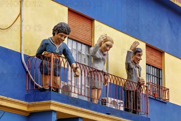 Figures on a balcony of a blue and yellow building in La Boca, the colourful city and tango