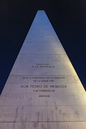 An illuminated obelisk with inscriptions in Buenos Aires at night against a deep blue sky, The