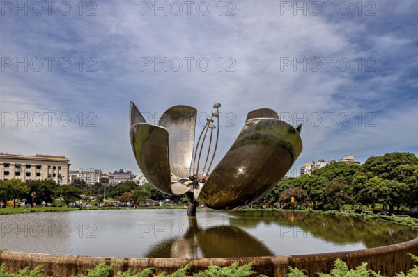 Metal flower sculpture near buildings with a cloudy sky in the background, The lotus blossom in
