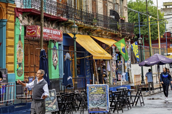 A lively street market with colourful banners and cafés, people stroll past, The colourful city and