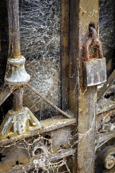 Detail of an old dilapidated door with cobwebs and a rusty lock, La Recoleta cemetery in Buenos