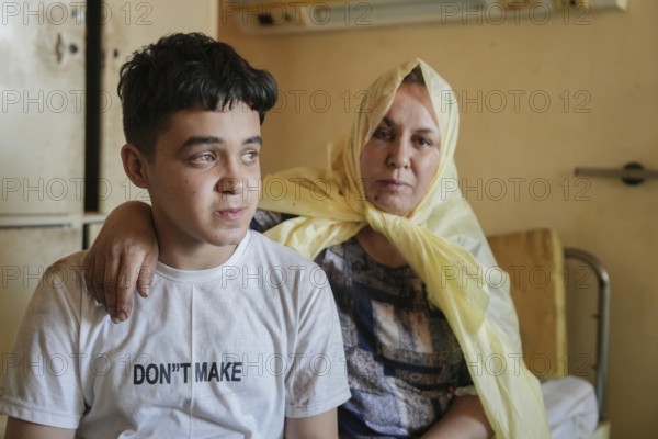 Wounded individuals receiving treatment at a hospital after being evacuated with difficulty from