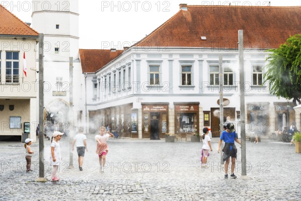 Water mist system in the city centre of Trencin, children use the refreshment in the summer heat,