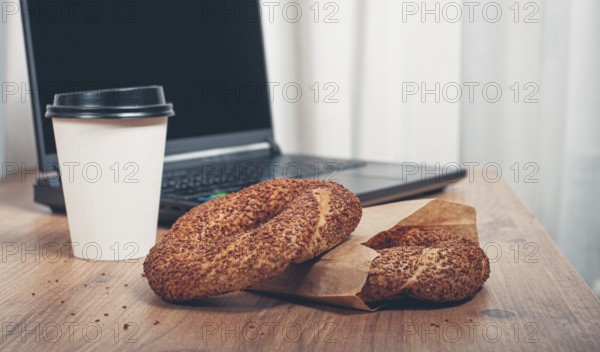 Simits with coffee on a wooden table, with a laptop, in a cozy working environment, snack,