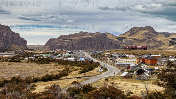 A small village nestled in a hilly landscape along a winding road, the village of El Chalten in