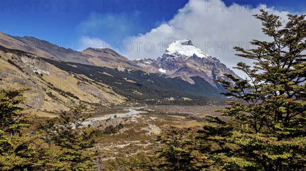 Wide valley with a river, surrounded by mountain peaks and wooded areas, The Patagonian landscape