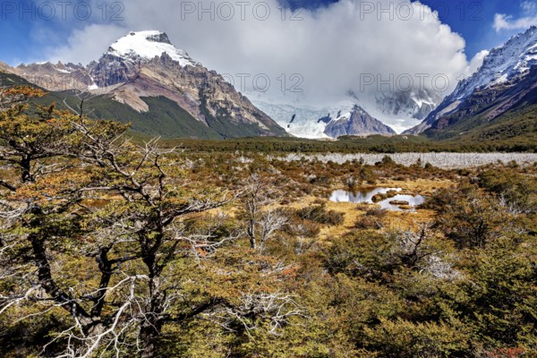 Snowy mountain scenery with wild foreland, clouds and a small pond in an autumnal landscape, The