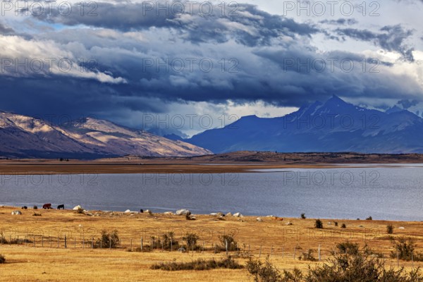 A wide lake under dramatically threatening clouds, surrounded by majestic mountains: the Patagonian