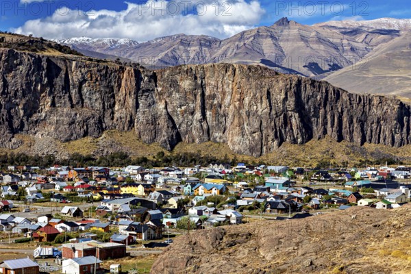 Village with colourful roofs at the foot of impressive cliffs and mountains in the background, the