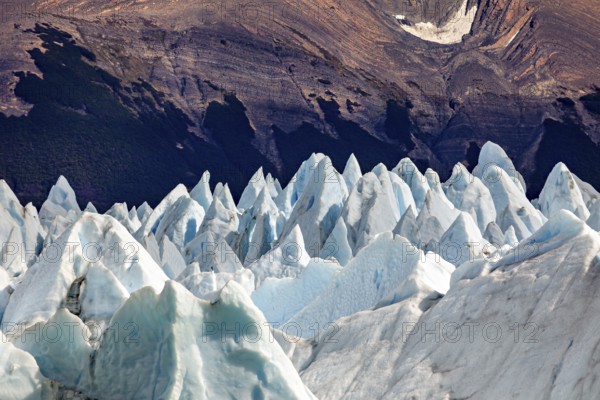 Pointed ice formations in front of a dark mountain landscape with an impressive natural backdrop,