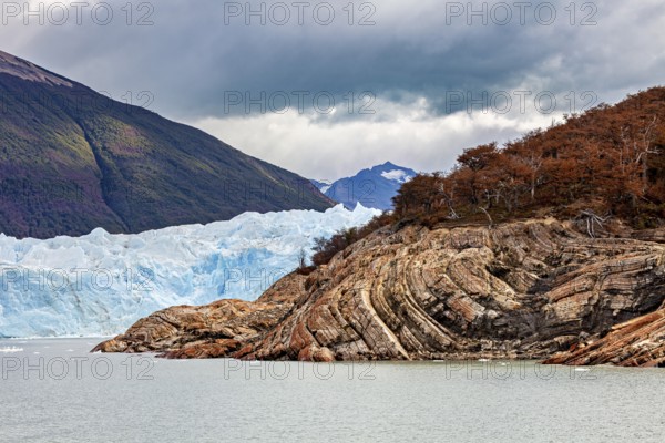 Frozen glacier water meanders between rocks and colourful forests, The Perito Moreno glacier in