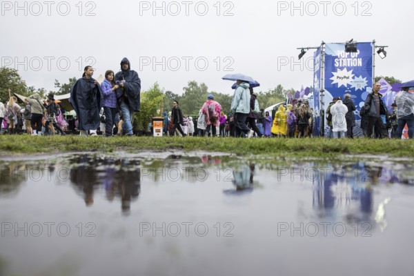 Festival-goers reflected in a puddle at the Lollapalooza Festival in the Olympic Stadium and on the