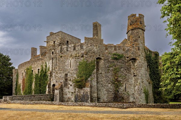 Stone castle with round towers and ivy growth under a cloudy sky, Pirou Castle in Normandy, France