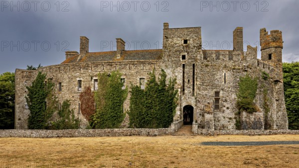 View of a stone castle with ivy and clouds in the sky, Pirou Castle in Normandy, France